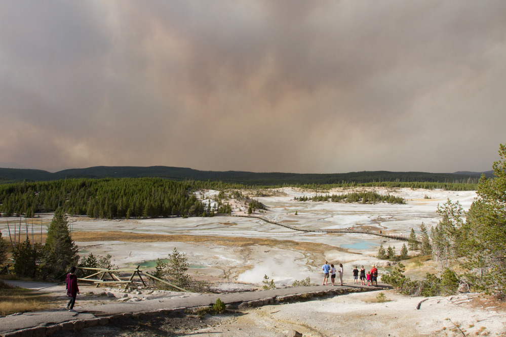 Visitors in Porcelain Basin at Norris Geyser Basin. Smoke filled sky from the Maple Fire