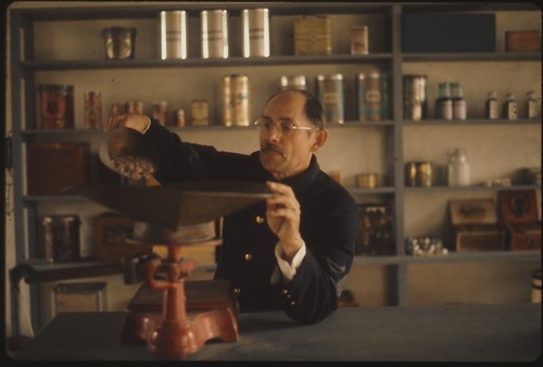 Commissary Sergeant at the Post Commissary weighing groceries on a vintage scale.
