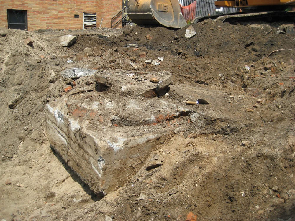 What we have here is the base of the carriage house turntable. Carriage houses of the wealthy would once have often contained a turntable so that the carriage could be turned and brought out front-forward. As cars became increasingly common, the turntables continued to be used for homeowners' new cars. New turntables even continued to be installed into the first couple decades of the 20th century. What we see here is the base which the turntable rotated on.