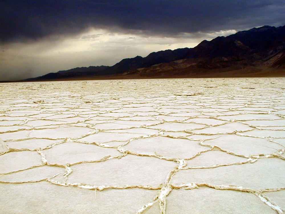 Surreal patterns of salt with a stormy backdrop.