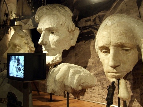 Plaster models of Thomas Jefferson (far left), Abraham Lincoln (center) and George Washington (far right) on display in the Exhibit Hall inside the Lincoln Borglum Visitor Center.  A plaster model of a hand is also diplayed between Lincoln and Washington.