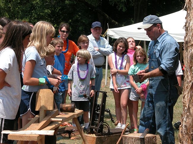 Children watching woodworking demonstration.