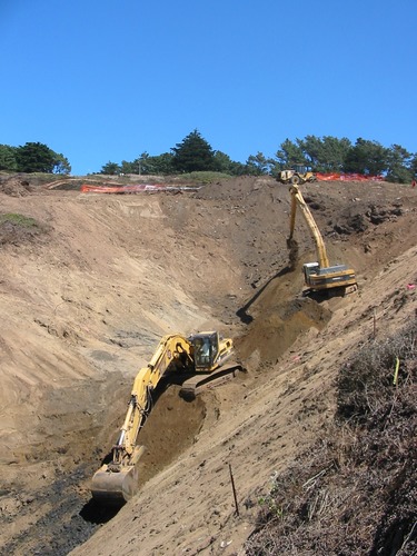 An excavator removes contaminated soil from an old Army landfill