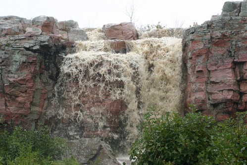 Water gushing over the Sioux Quartzite cliffs creating a temporary waterfall.