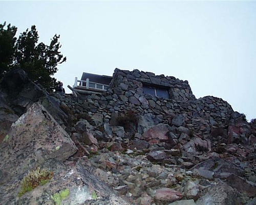 The rock structure of the observation station appears to grow out of the natural rock formations of a hillside.