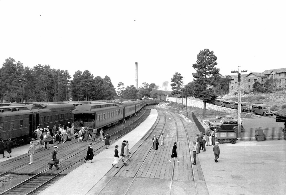 Park visitors arriving by train at Grand Canyon National Park's Santa Fe Railroad Depot. Tour busses waiting on the right. 11 August 1939. NPS photo.