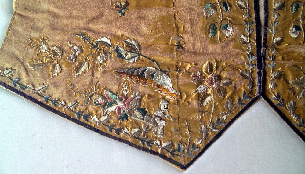 In this detail, a small chinese figure plays a flute, surrounded by flowers.