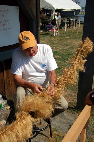 NPS volunteer Bill Bradbury demonstrates how to make baggywrinkle, which is used to prevent chafing in the ship's rigging
