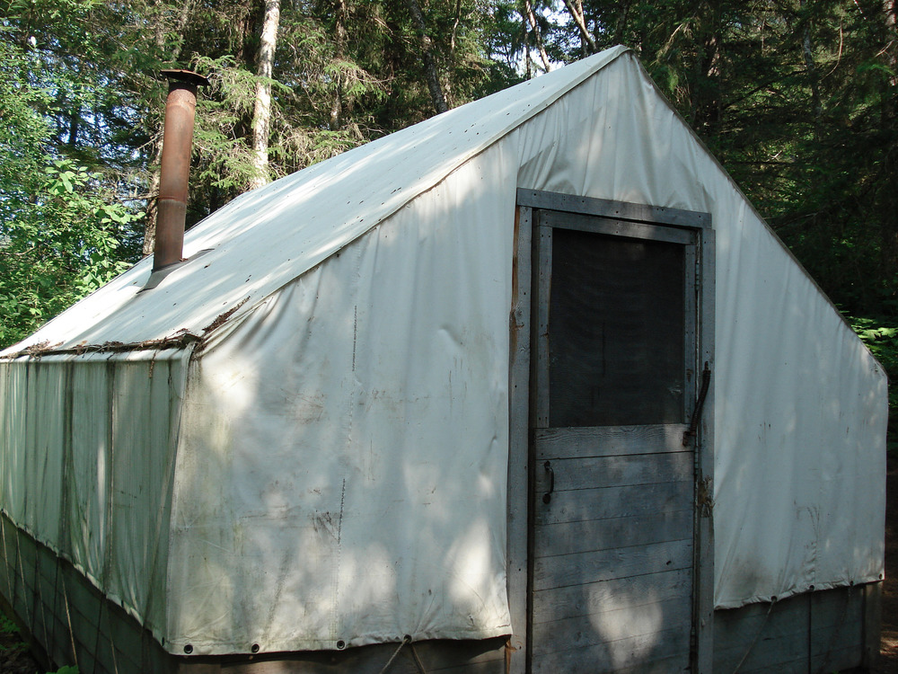 White wall tent with screen door and metal chimney