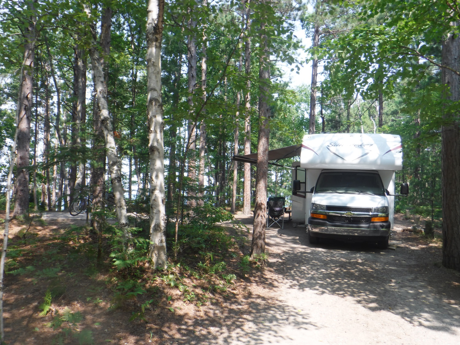 Twelvemile Beach Campground site 24,  in a wooded setting with a small RV on the site.