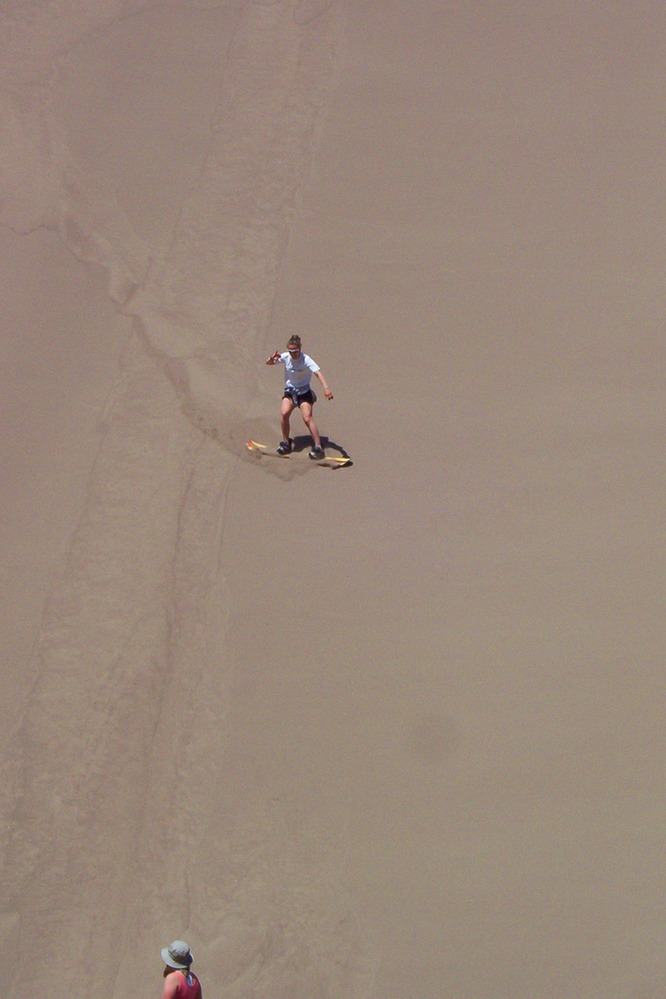 Two women sandboard near the Castle Creek Picnic Area, a stop along the Medano Pass Primitive Road. Visit our sandboarding, sledding, and skiing page for details.