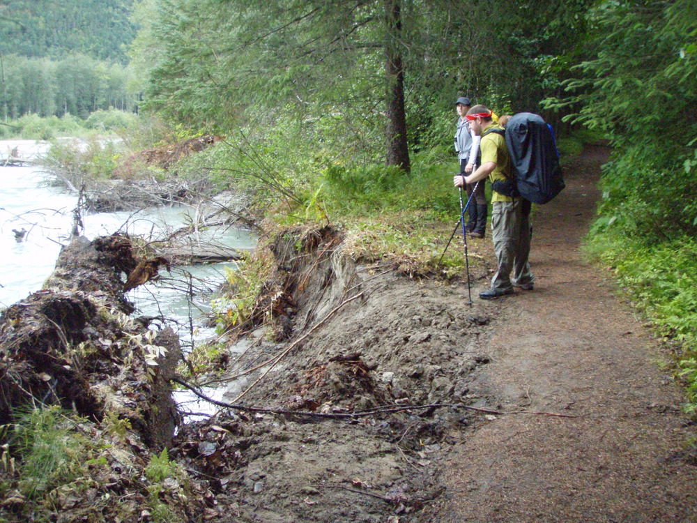 Two people on trail near slumping bank.