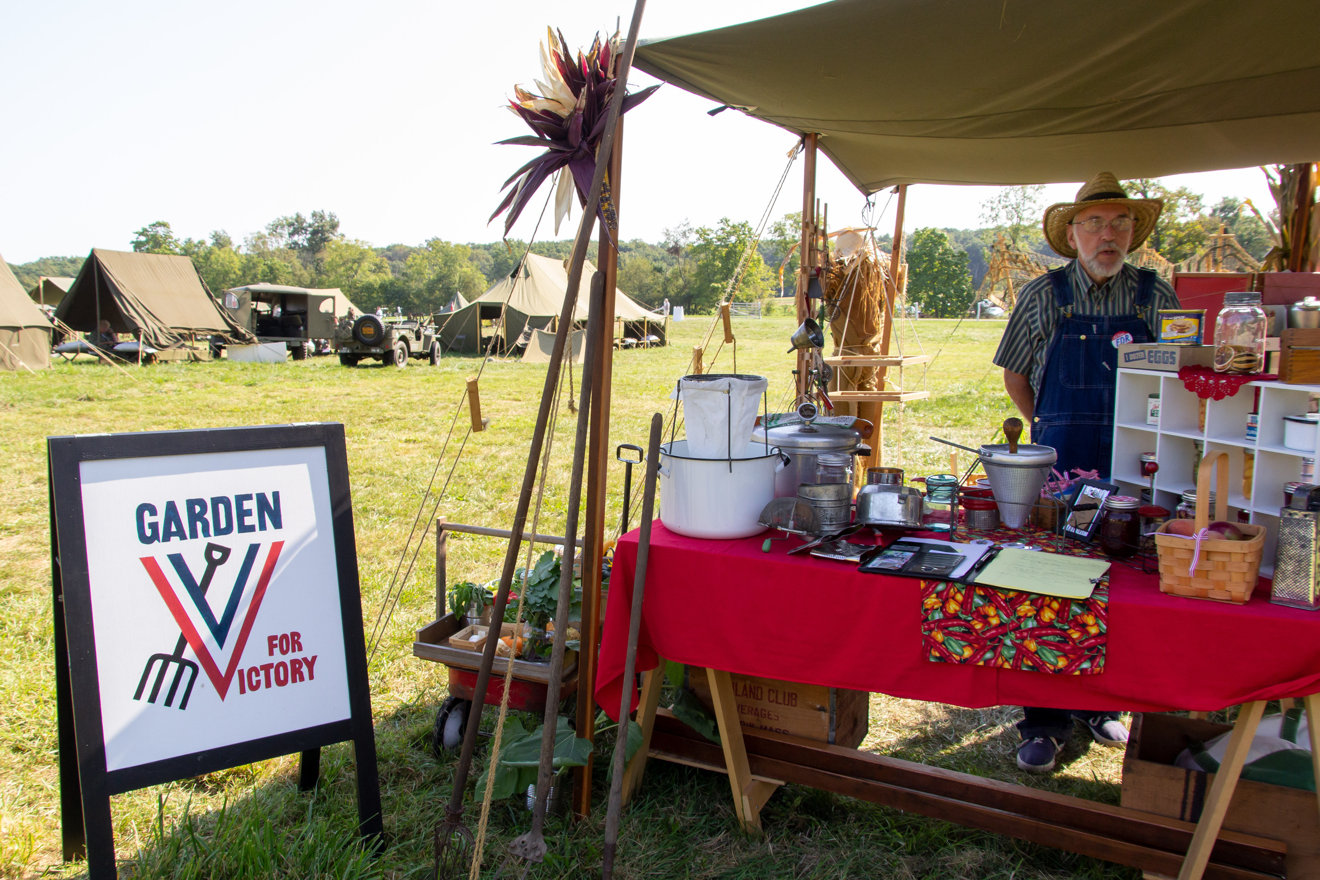 A man in overalls standing at a living history home front farm stand.