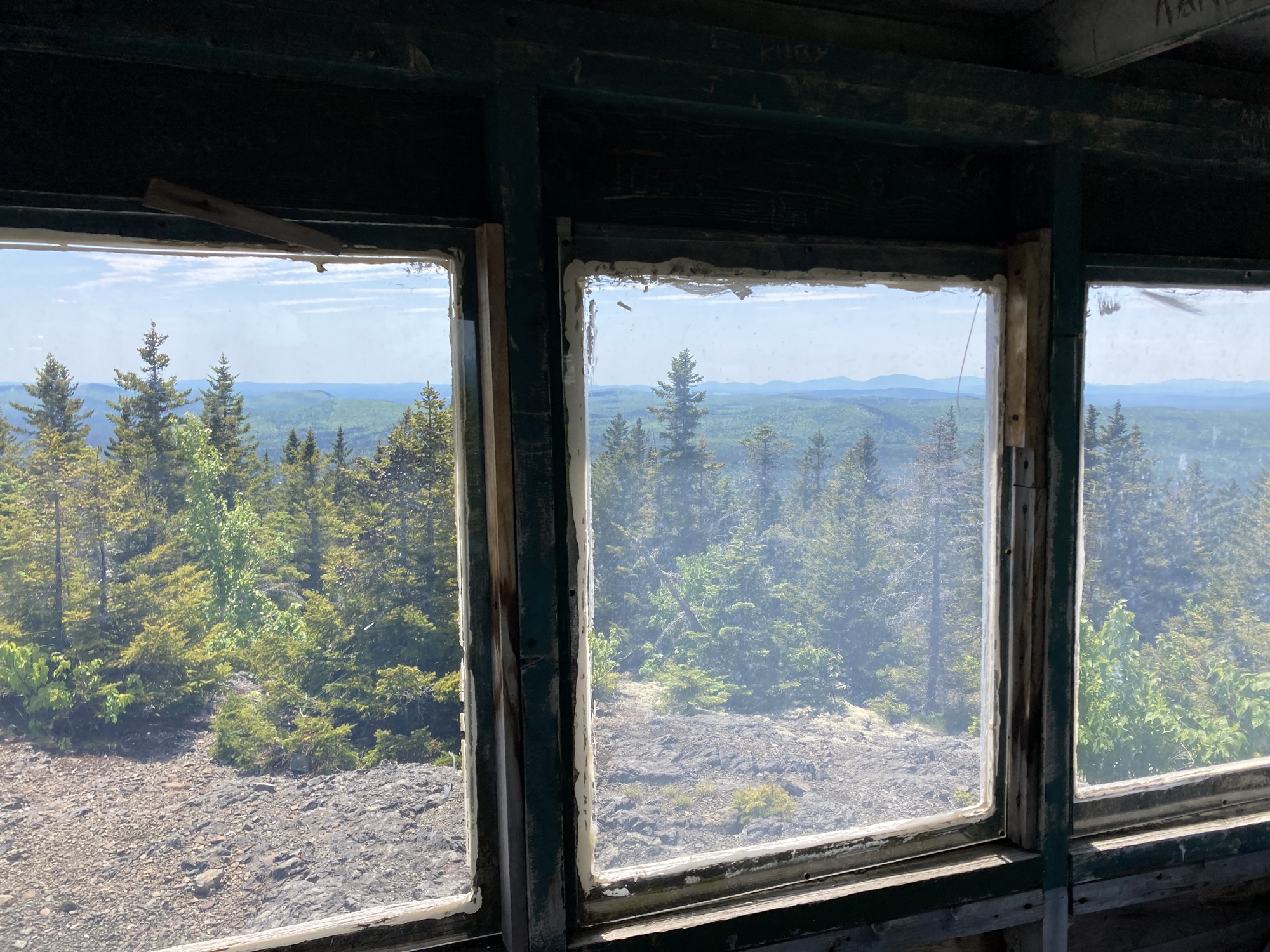 The view of forest and mountains from a three paneled window.