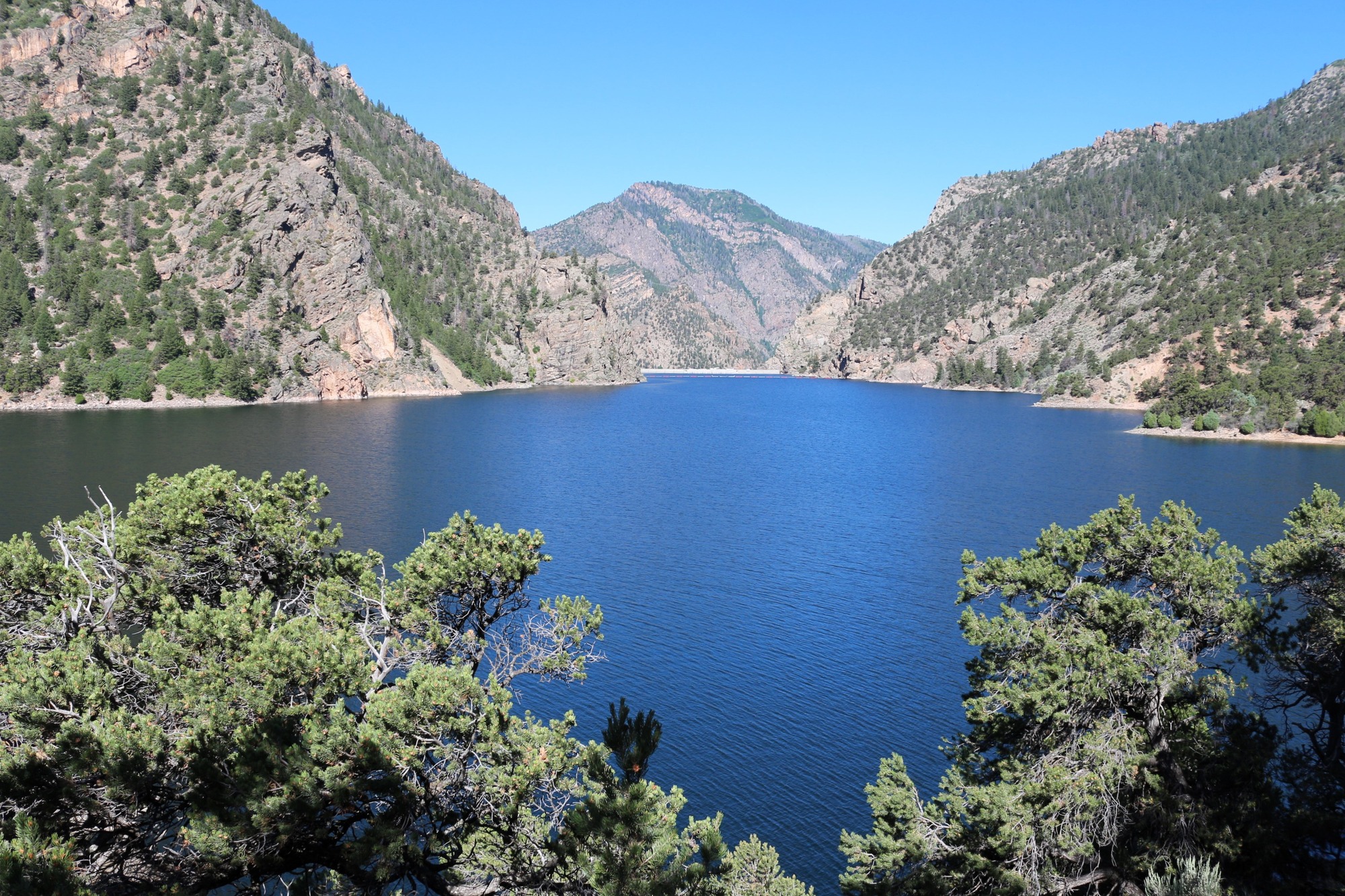 A large body of blue water between hills and sloping canyon walls