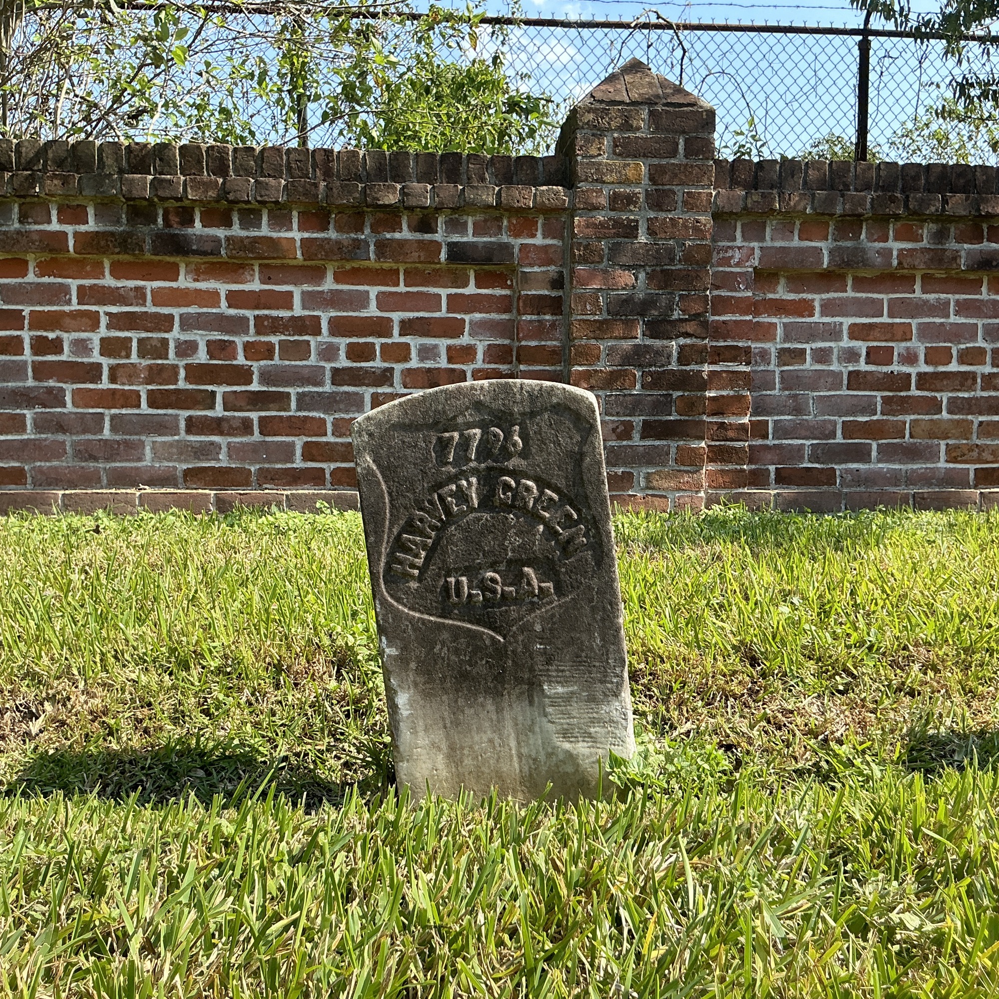 Front of historic upright marble headstone with recessed shield with recessed lettering face.