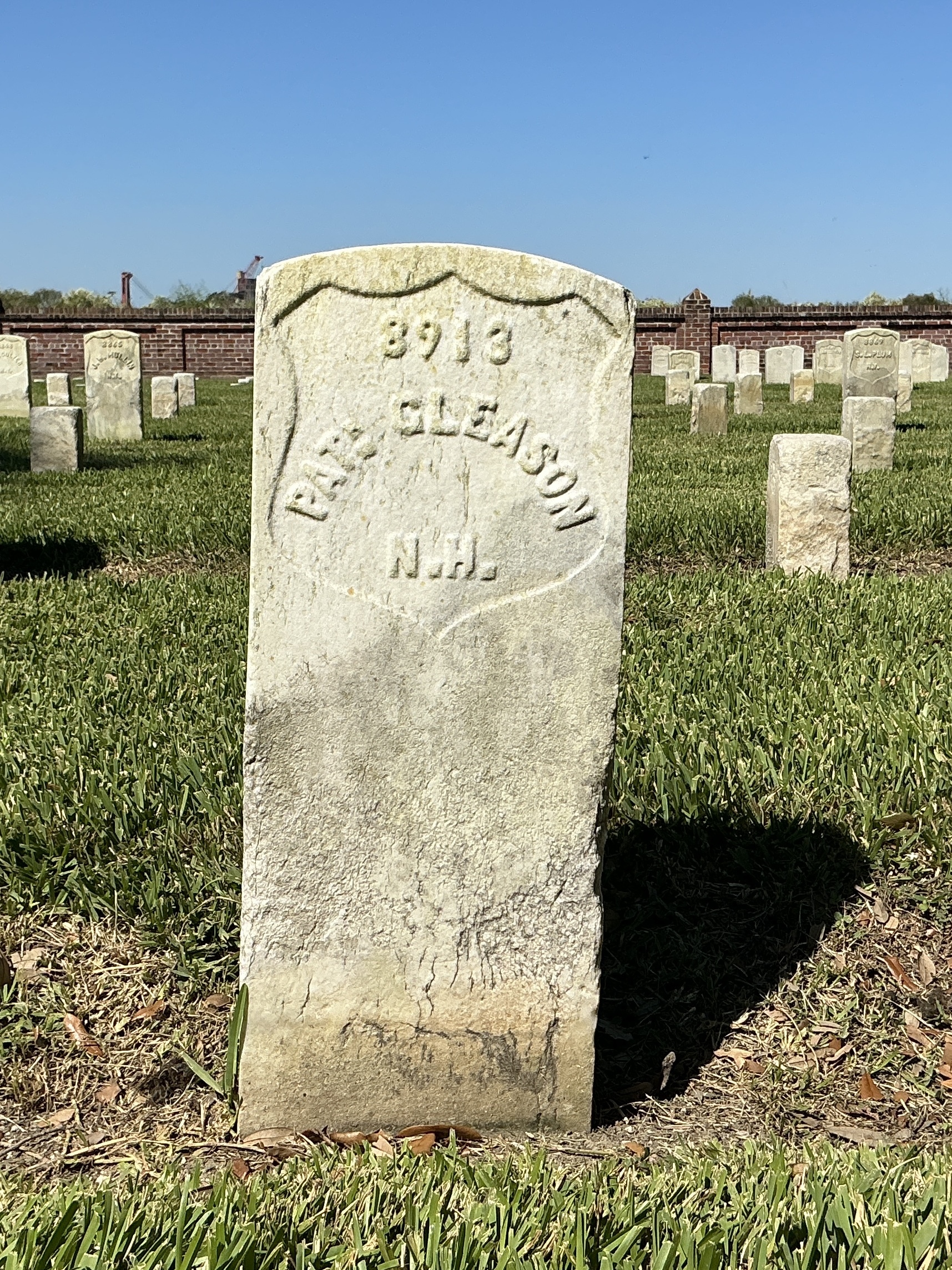 Front of historic upright marble headstone with recessed shield with recessed lettering face.