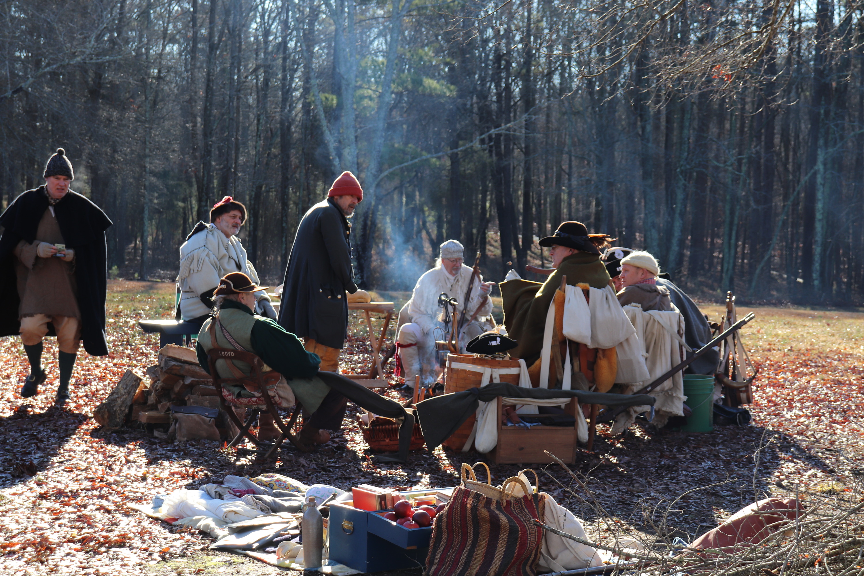 A large group of historians dressed as Militia make sit around a camp fire while they make camp at the Cowpens during the celebration.