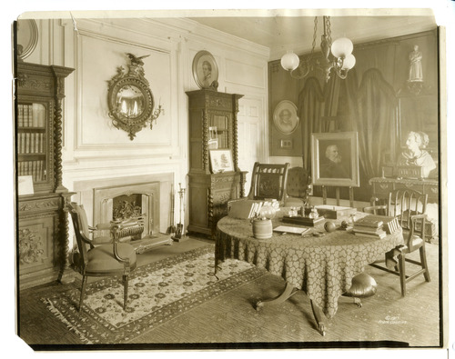 Black and white photograph of 19th century study, two renaissance revival bookcases are on either side of the fireplace.