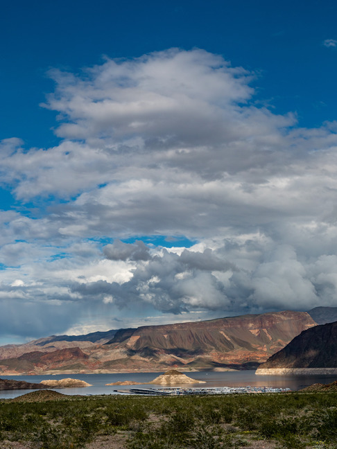 foliage, lake with marina, flat topped mountain and cloudy sky in distance