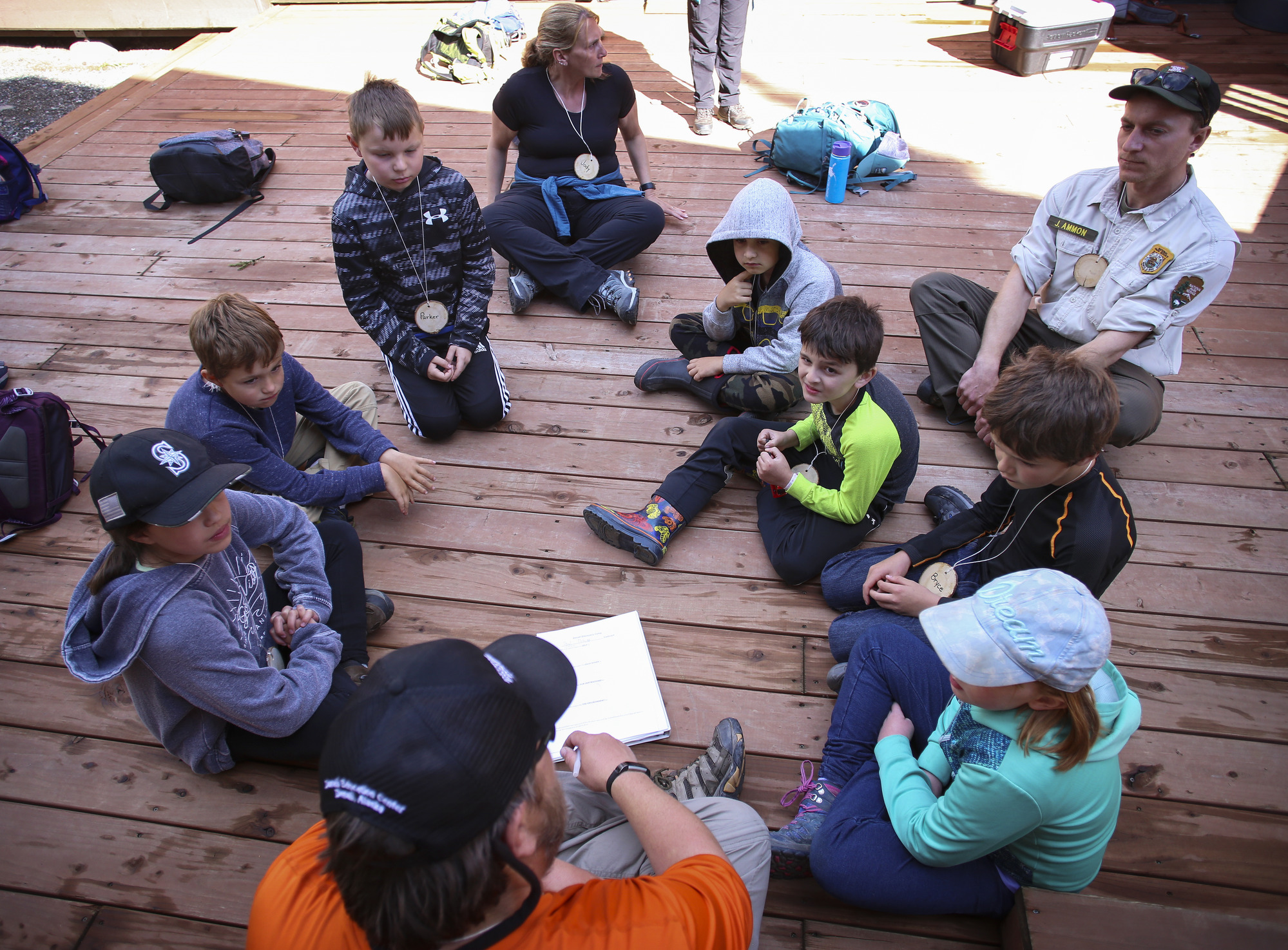 a park ranger and kids sitting in a circle on a deck