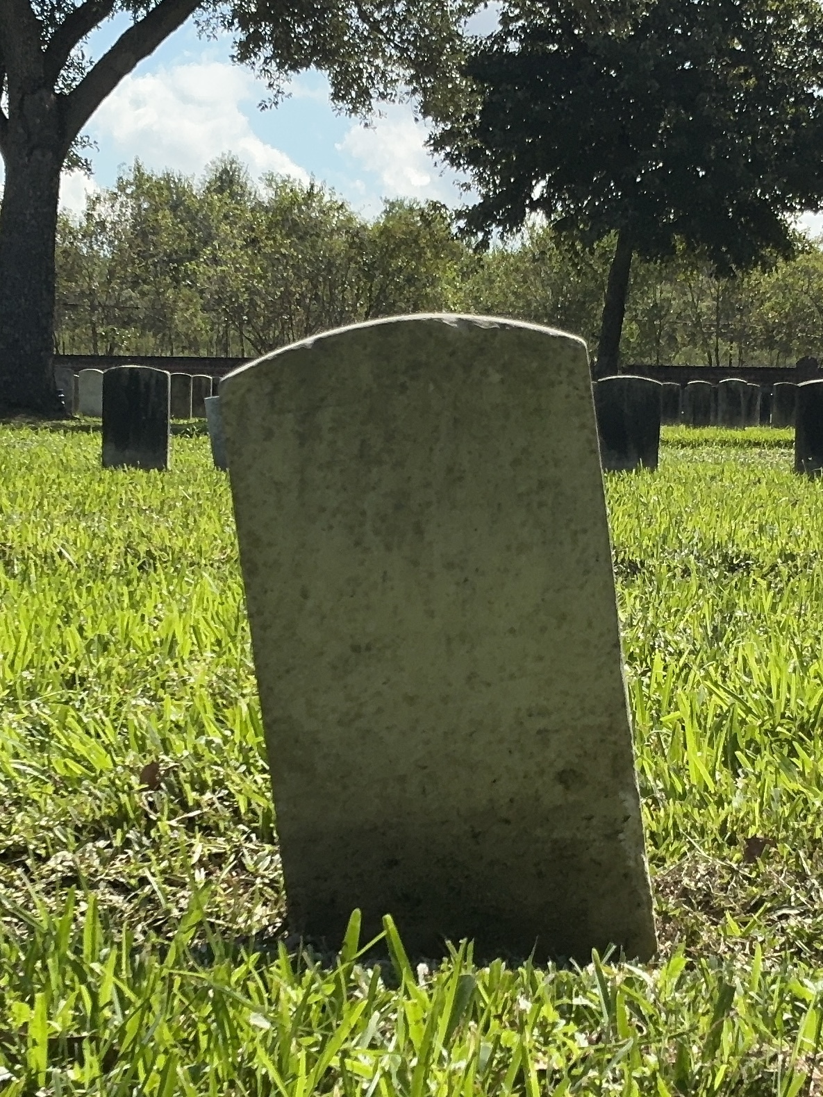 Back of historic upright marble headstone with recessed shield face.