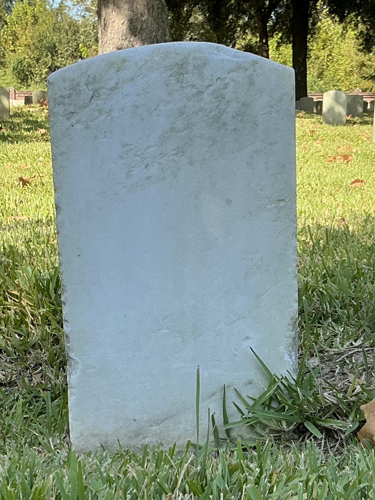 Back of historic upright marble headstone with recessed shield with recessed lettering face.
