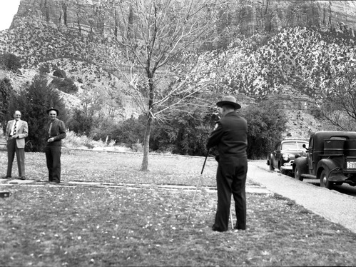 Ranger sets up camera by the ranger dormitory to photograph the attendees of the All-Area Staff Meeting. Meeting held at Zion National Park on December 5, 1952.