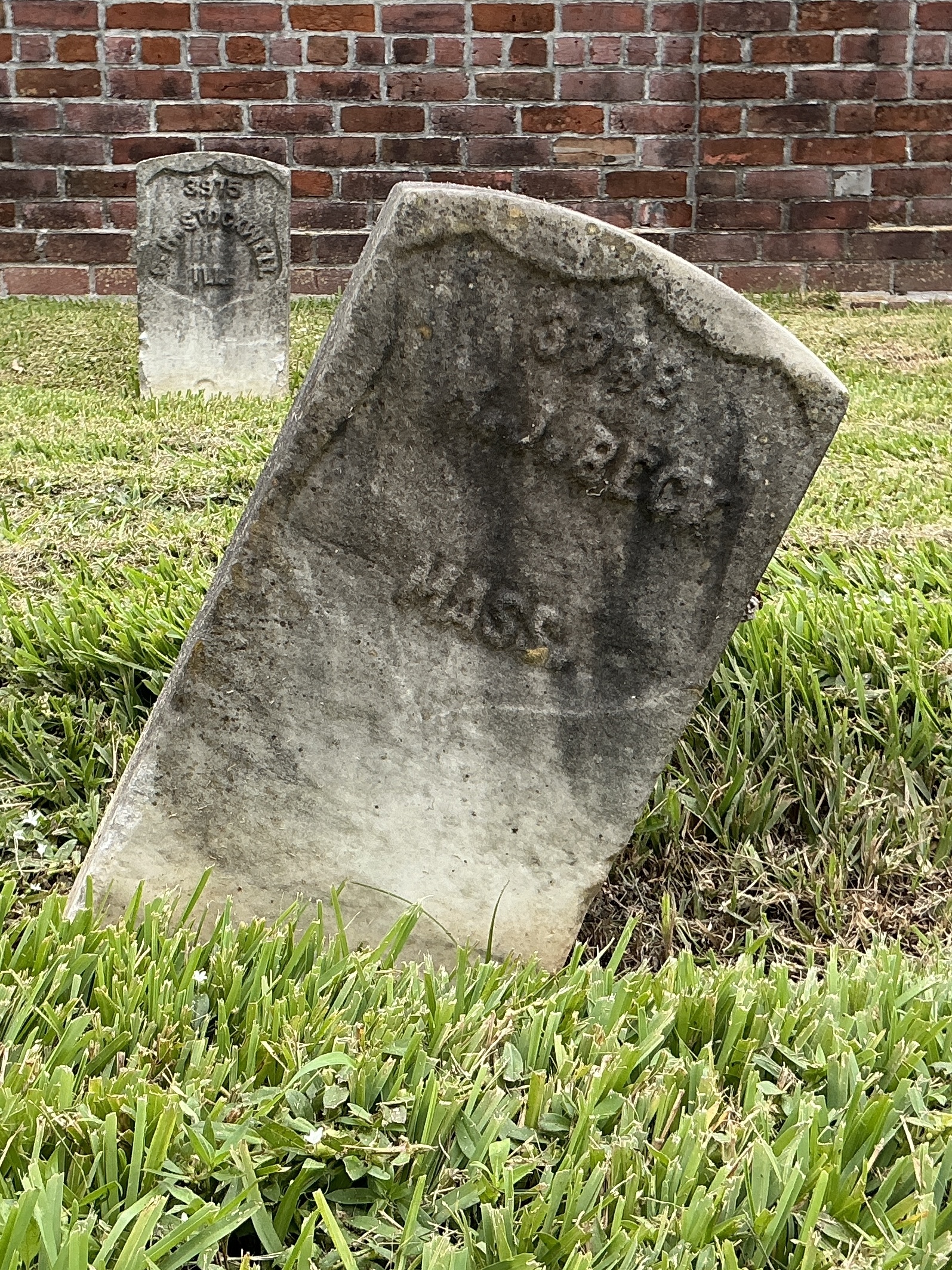 Front of historic upright marble headstone with recessed shield face.