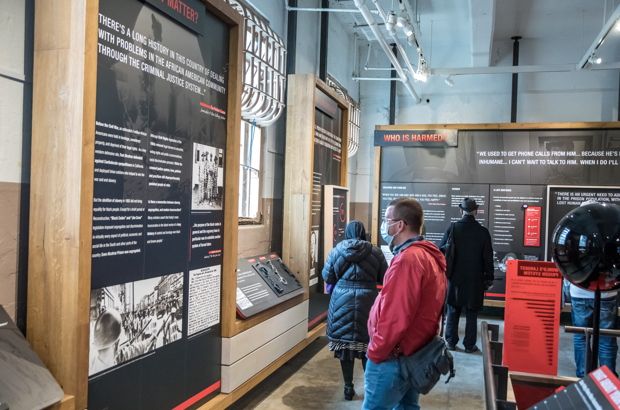 Black, white and red exhibit panels with the history of what led to mass incarceration and who it has impacted. Panels include quotes, text, images, and graphs.  