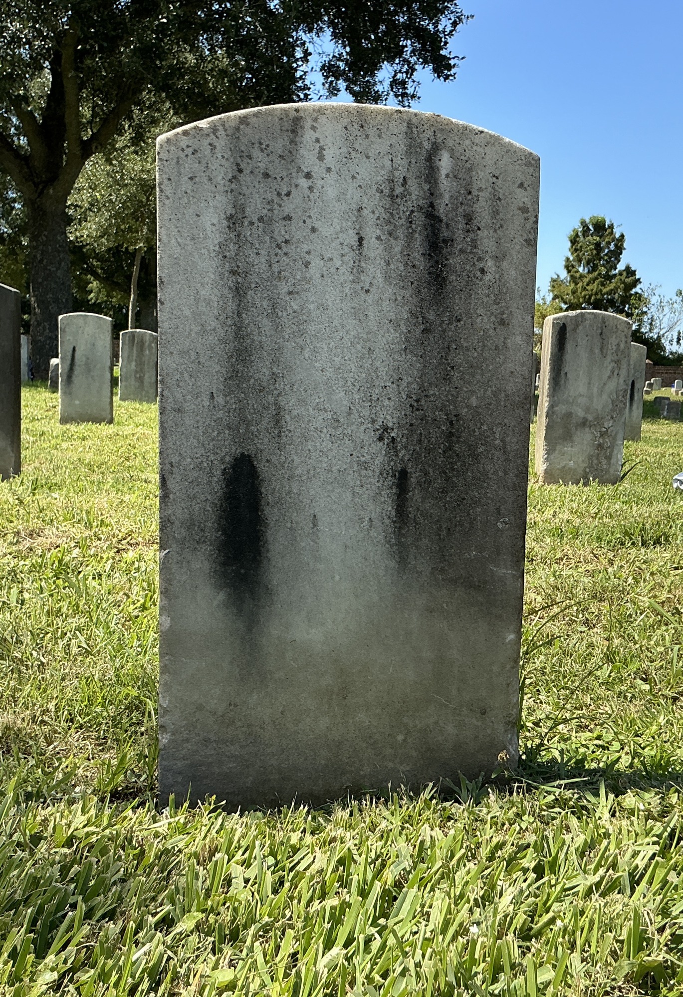 Back of historic upright marble headstone with recessed shield face.