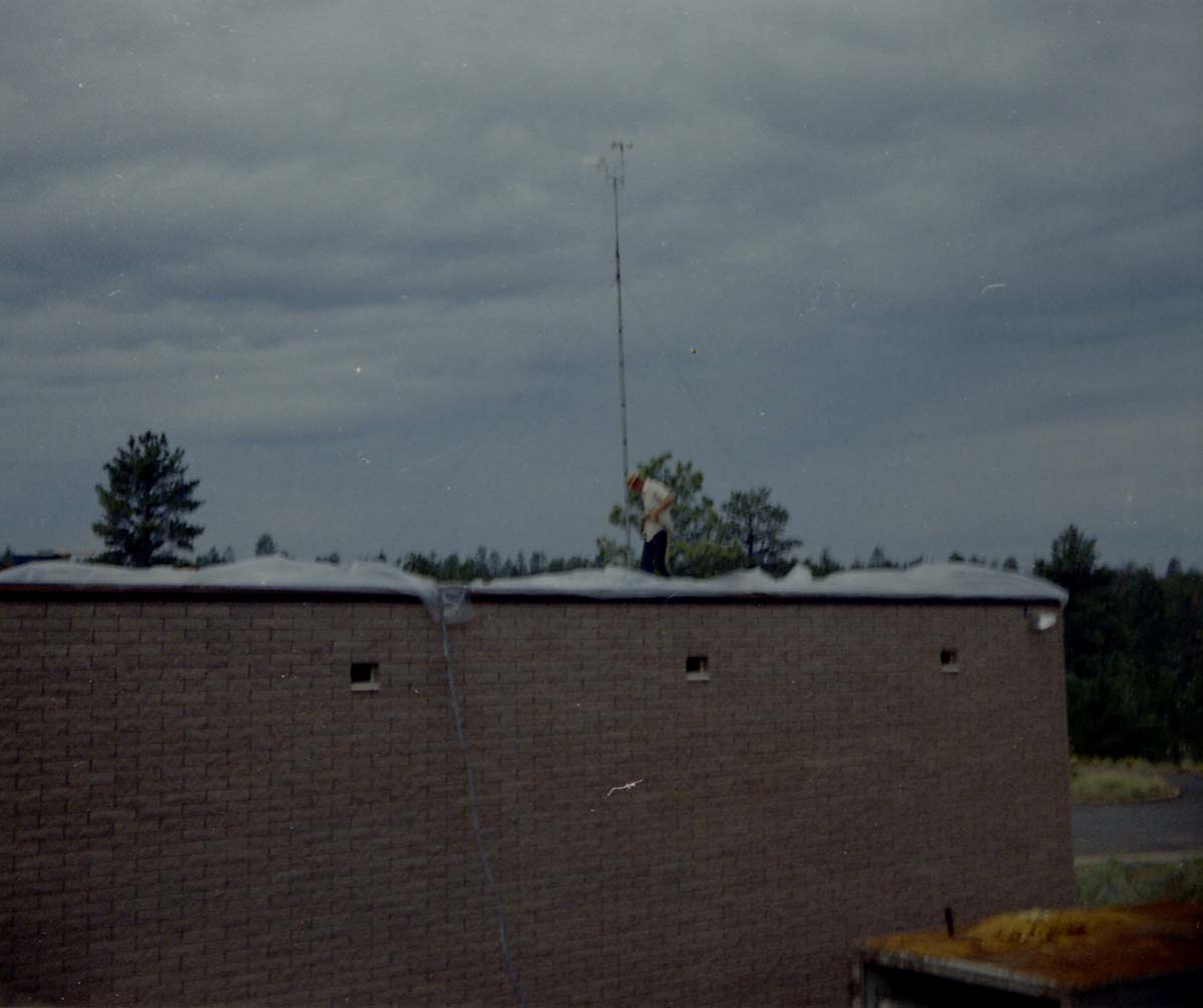 Man spraying foam sealant during reroofing project, plastic sheeting along edges of roof. Bryce Canyon National Park.