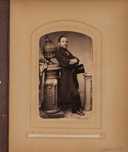 Black and white photograph of man posed between two small pedestals.