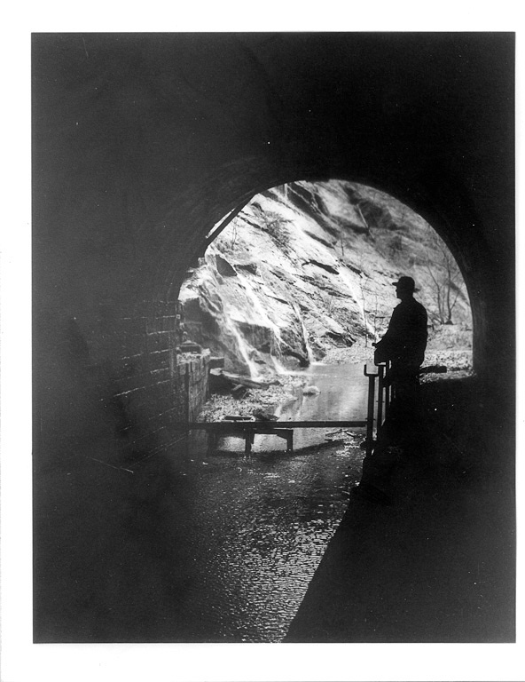 Historic photo of a silhouetted of a person standing at one end of the Paw Paw Tunnel