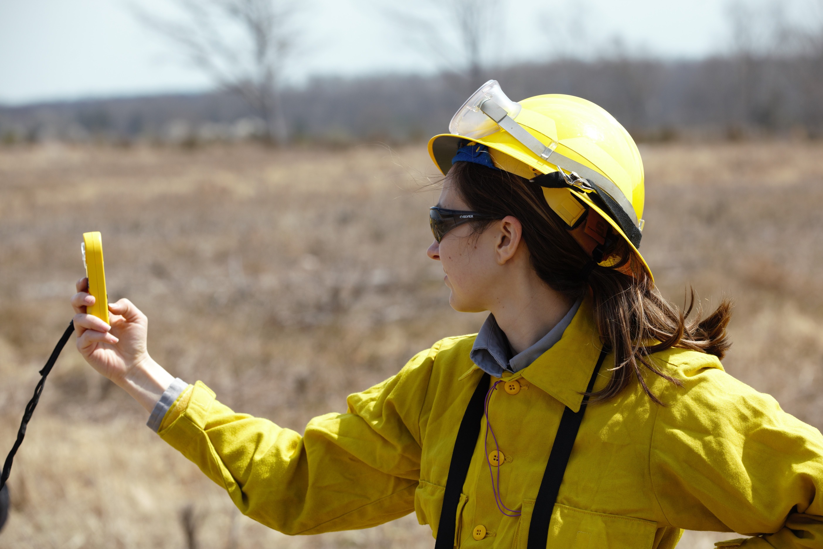 A firefighter in Nomex holds a piece of equipment to take weather readings.