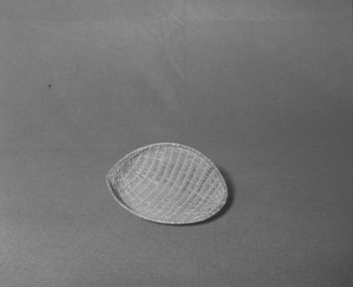 Mrs. Donald Segerstrom Collection. Object: Western Mono model winnower. Dimensions: 7 1/2 x 6 1/4". Materials: Redbud, with ceanothus rimstick. Technology: Diagonally twined, up to right slant of turns, single rimstick attached by beginning at base and coiling around and over original start. Photographed by Michael Dixon. Catalogued by Craig Bates and Barbara Beroza. Yosemite Collections, National Park Service. 1/83.