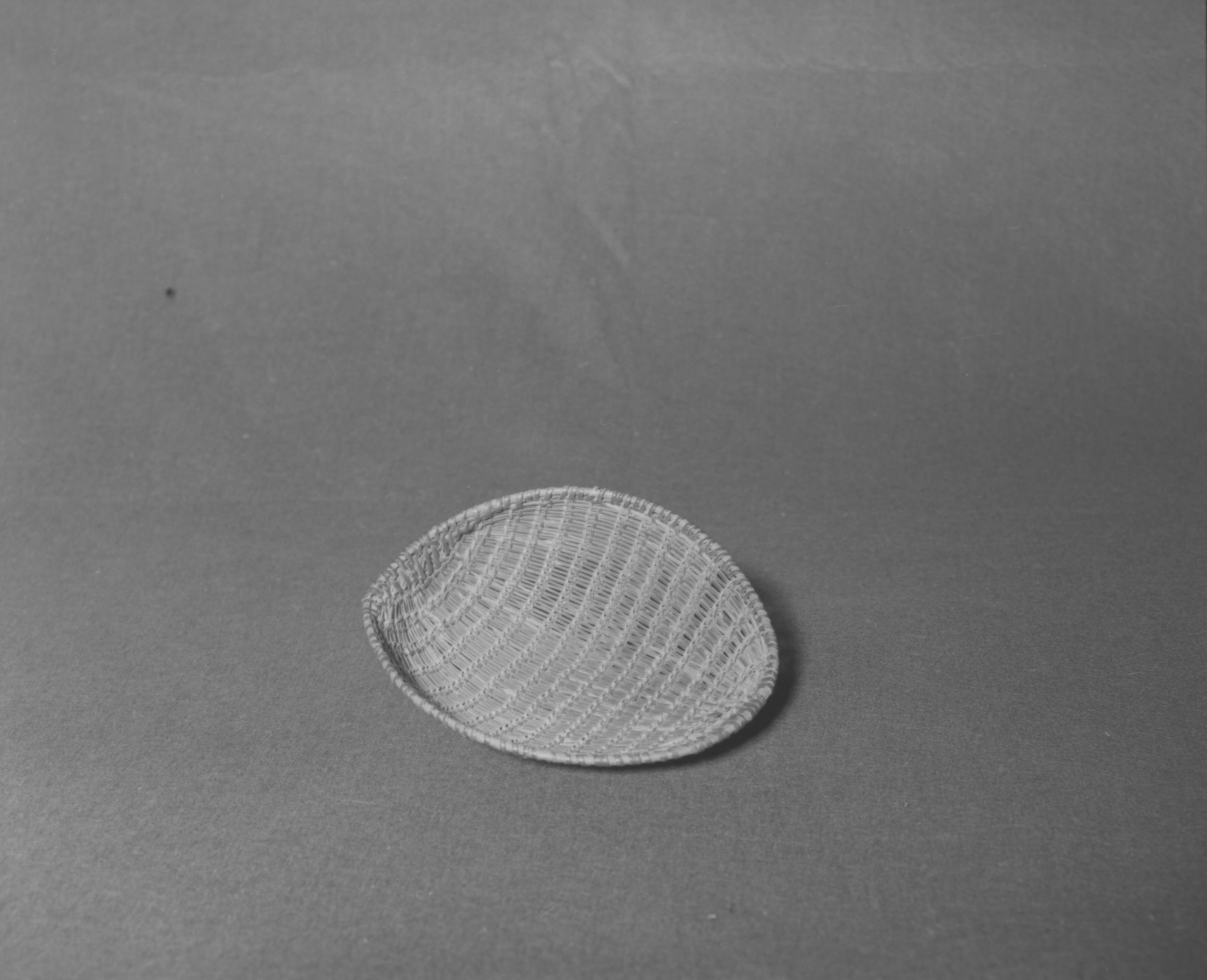 Mrs. Donald Segerstrom Collection. Object: Western Mono model winnower. Dimensions: 7 1/2 x 6 1/4". Materials: Redbud, with ceanothus rimstick. Technology: Diagonally twined, up to right slant of turns, single rimstick attached by beginning at base and coiling around and over original start. Photographed by Michael Dixon. Catalogued by Craig Bates and Barbara Beroza. Yosemite Collections, National Park Service. 1/83.