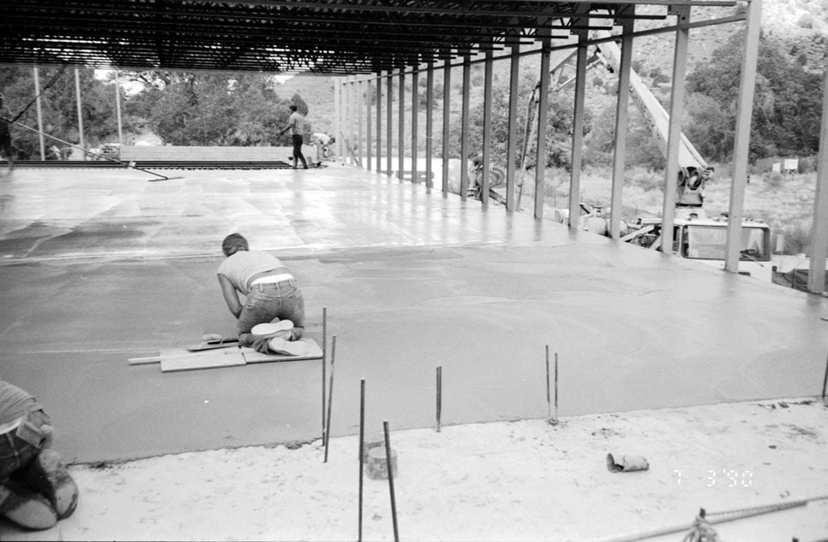 Workers leveling cement in corner during construction of headquarters addition.