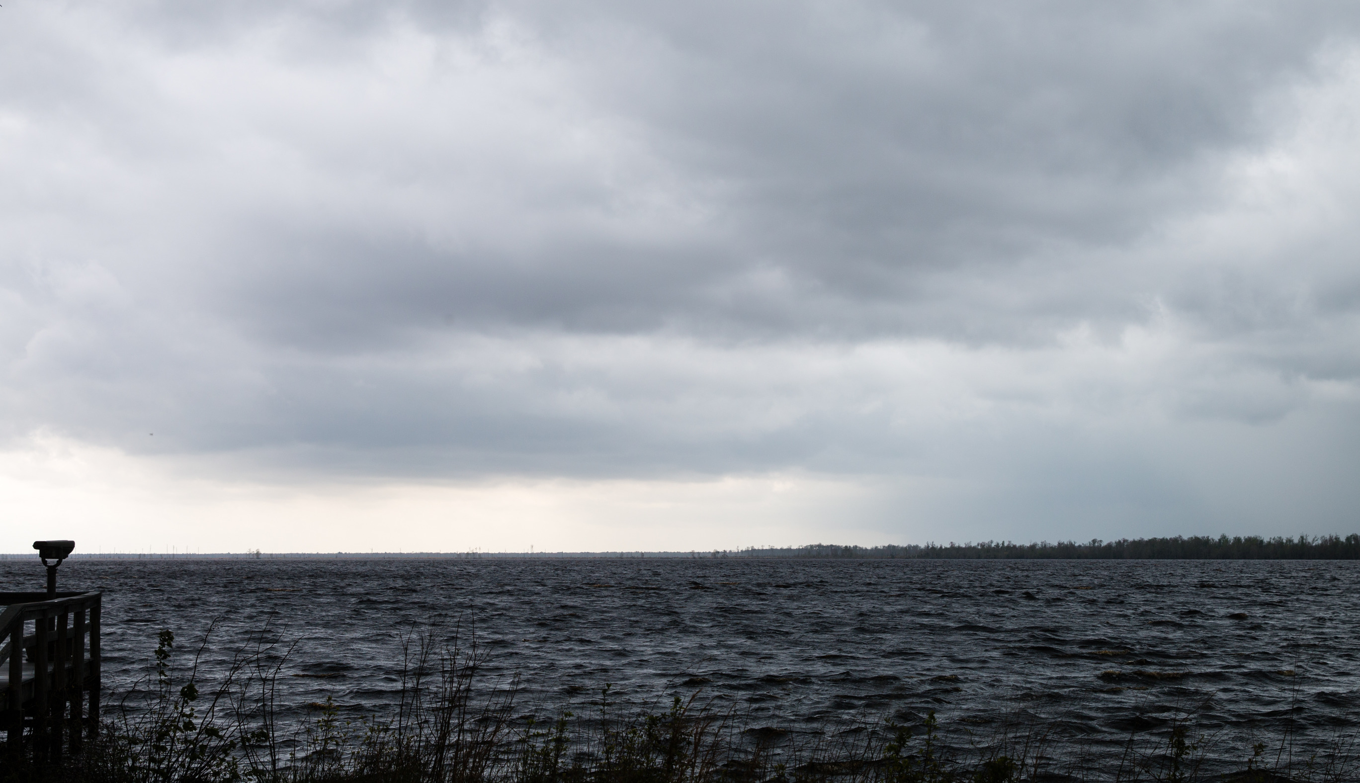 dark choppy waters with a cloudy sky and a wooden dock and viewfinder in the left hand corner