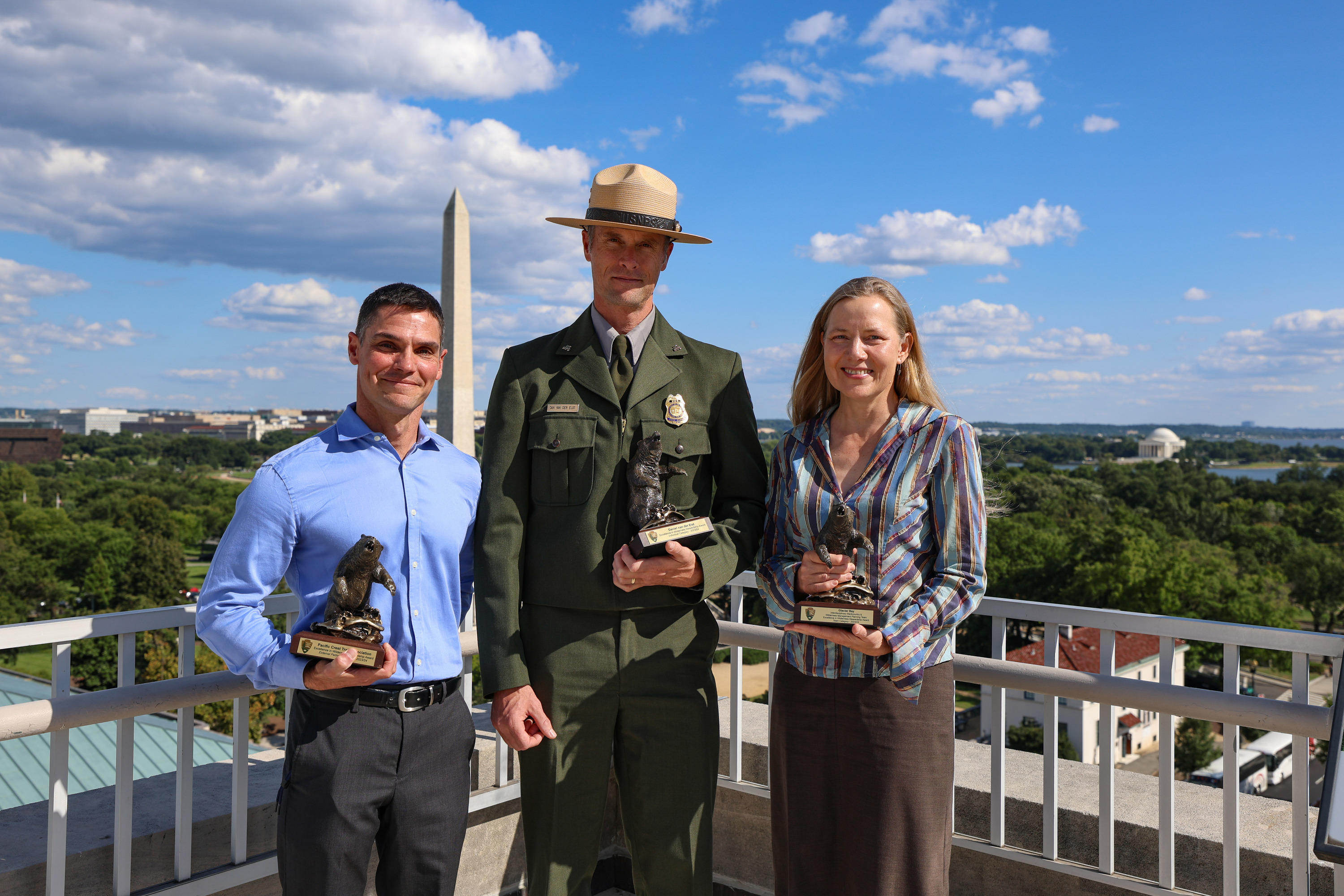 Three award recipients pose for a photo on a rooftop.