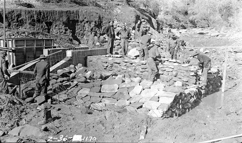 Civilian Conservation Corps (CCC) workers and park laborers engaged in diversion dam construction rock work.