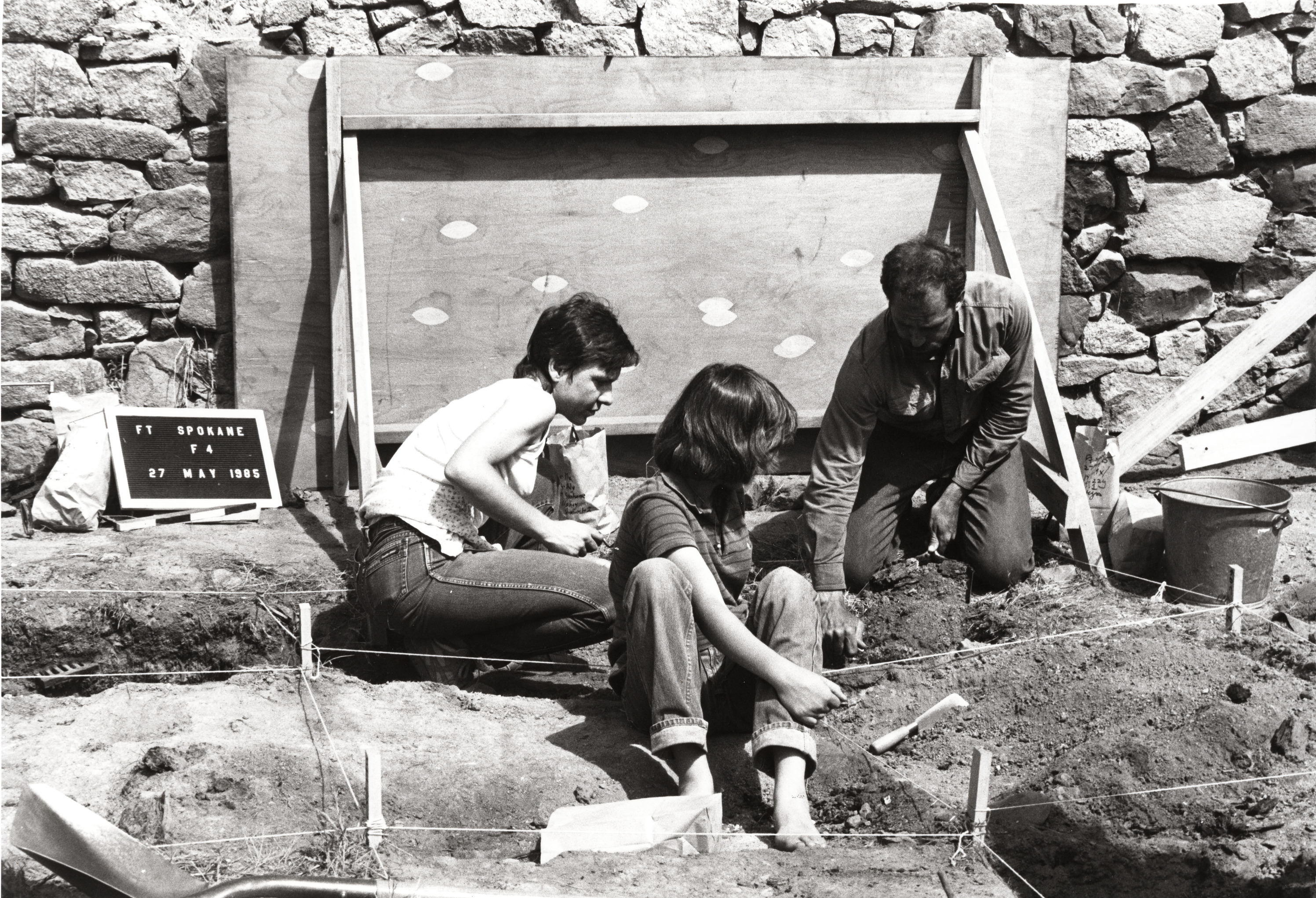 Black and white photograph of three people at archeological dig