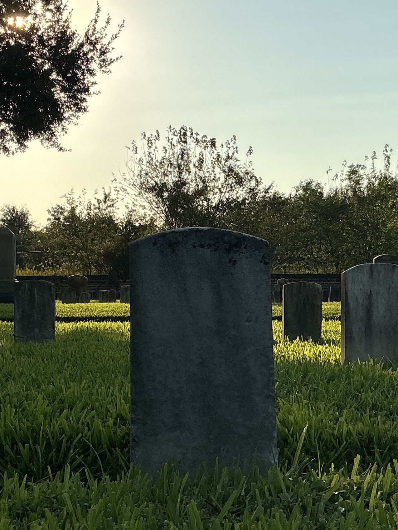 Back of historic upright marble headstone with recessed shield face.