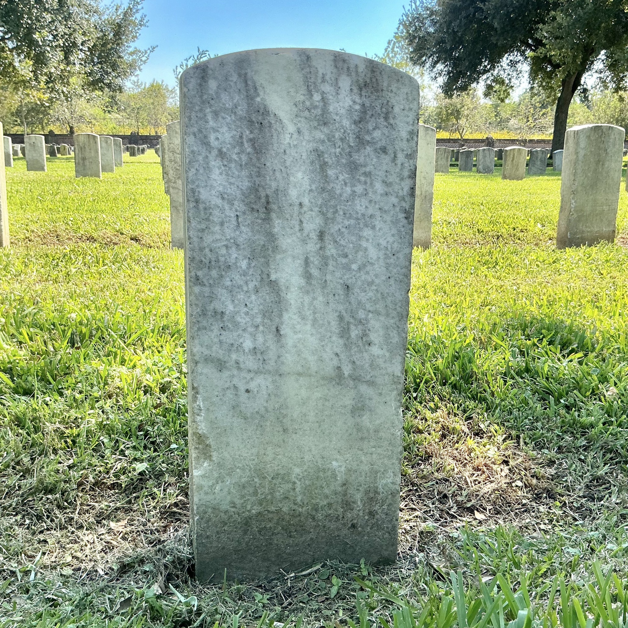 Back of historic upright marble headstone with recessed shield face.