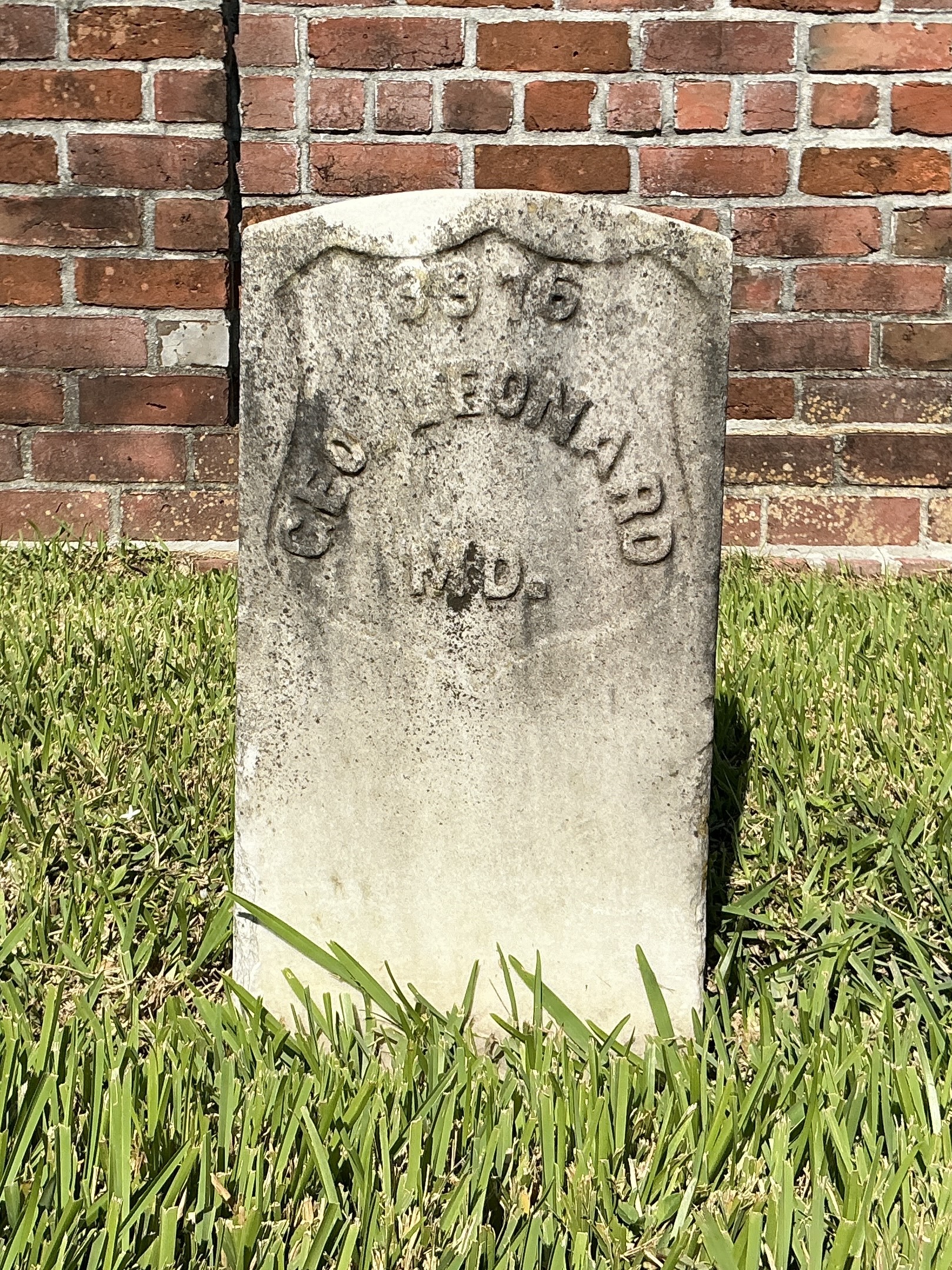 Front of historic upright marble headstone with recessed shield face.