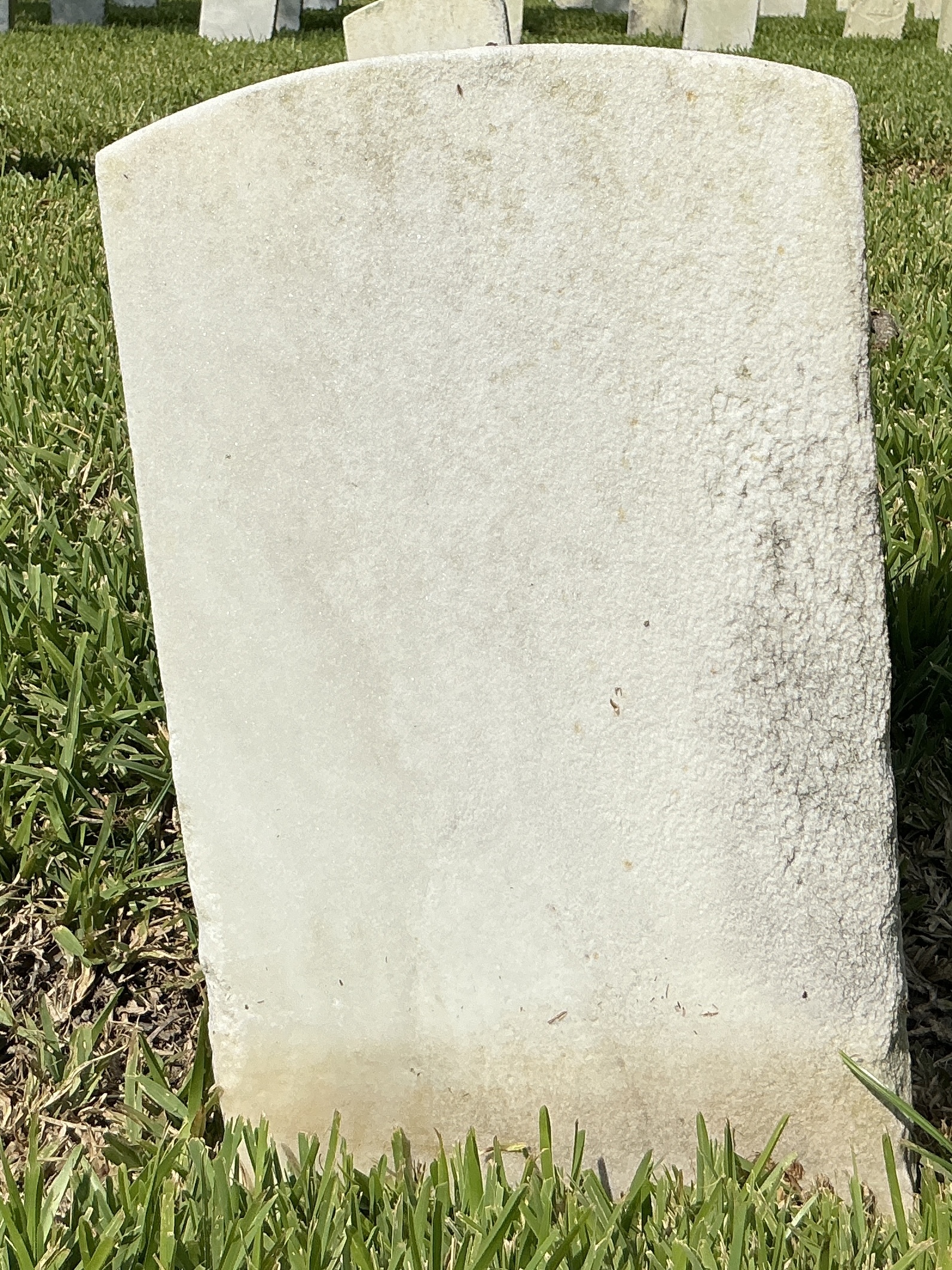 Back of historic upright marble headstone with recessed shield face.
