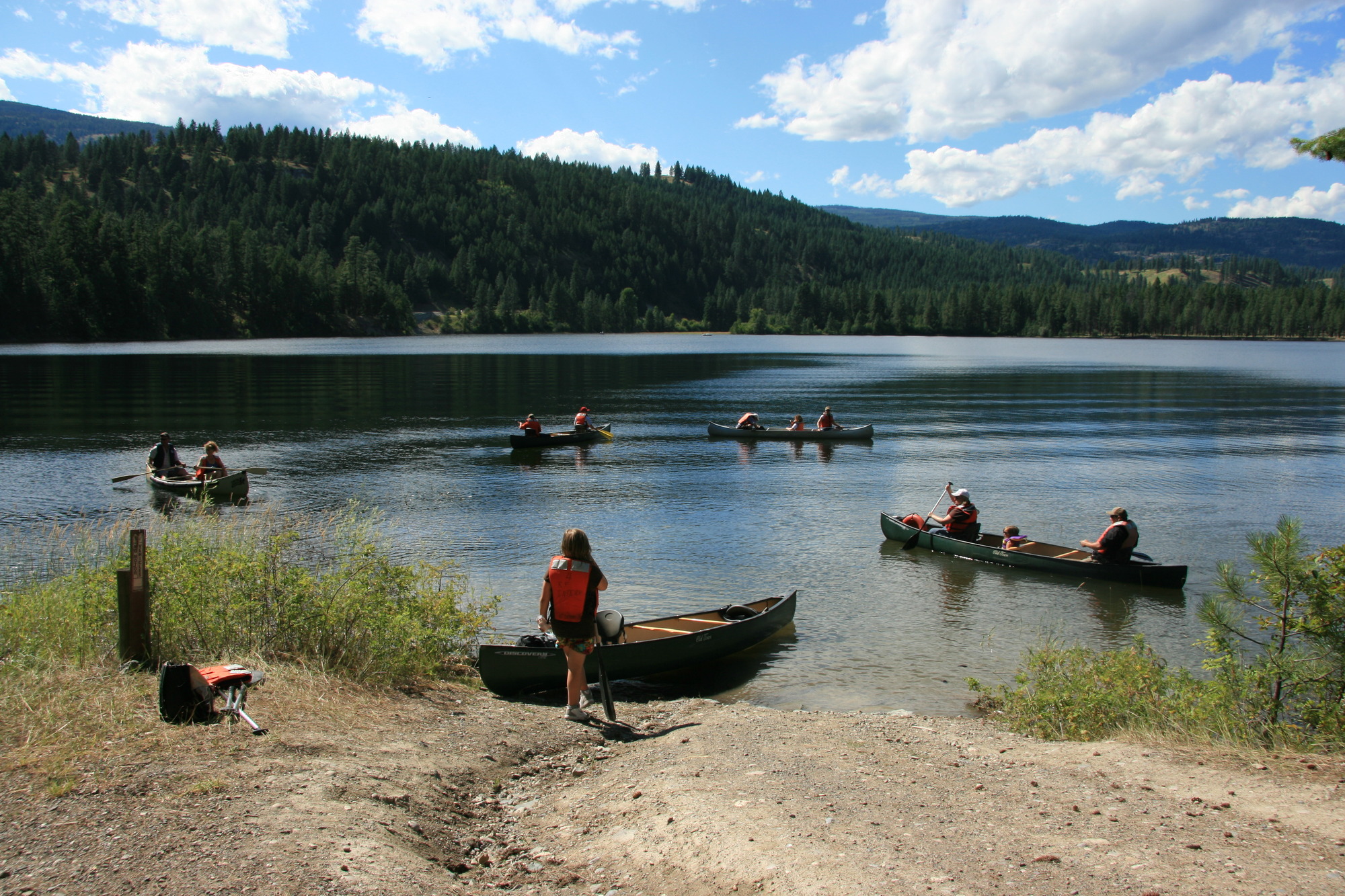 Color photograph of canoes in a lake as another waits on shore