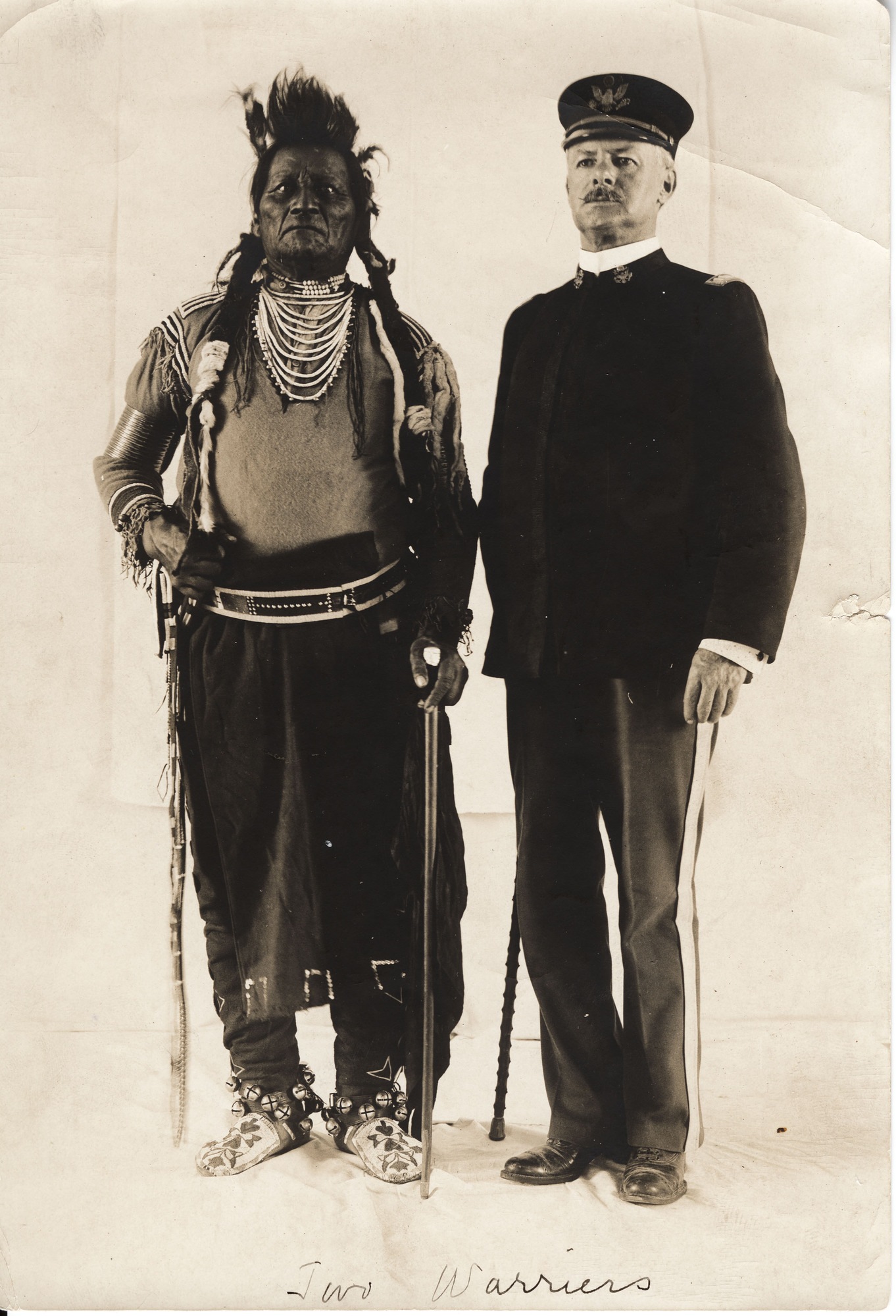 Black and white photograph of an American Indian man and a White man in uniform standing for a portrait