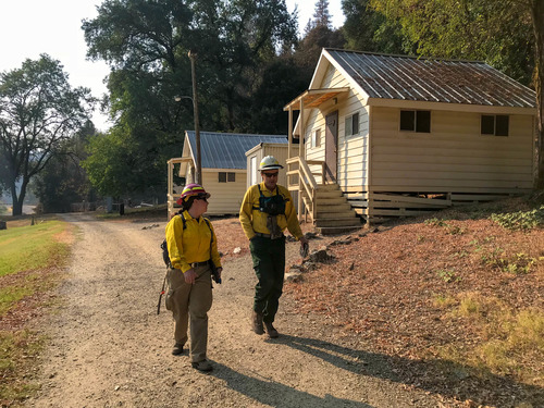 A hydrologist and geologist in protective clothing walking past cabins