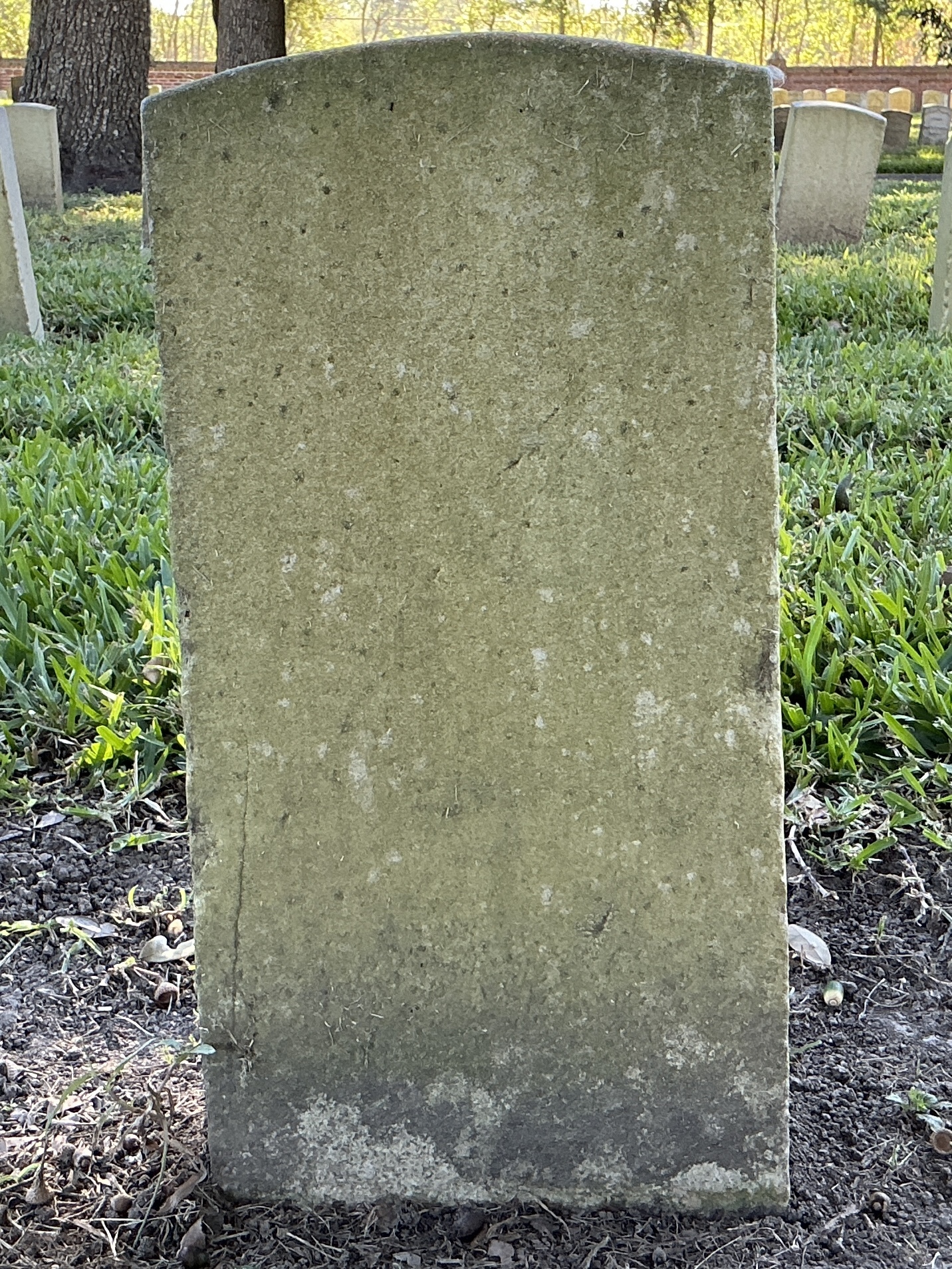 Back of historic upright marble headstone with recessed shield face.